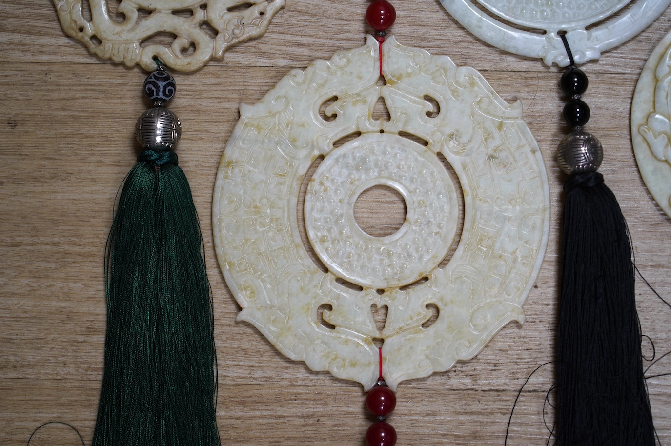 Four large Chinese carved bowenite jade discs, largest diameter 19cm, with tassel and bead wall hangings. Condition - fair to good